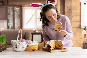 A woman holds a traditional Easter cake on the table.