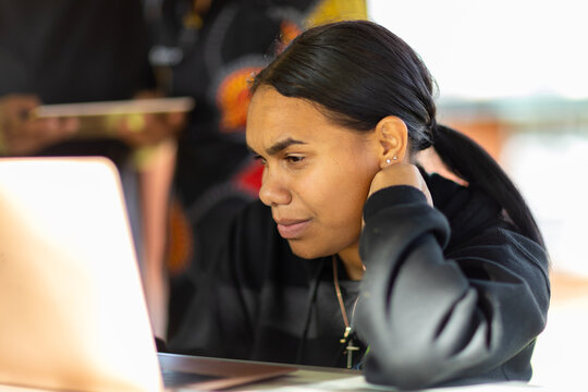 student leaning on elbow looking at laptop