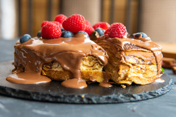 Pancakes with dessert filling and berries on a dark background.