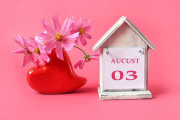  Calendar for August 3 : the name of the month of August in English with the numbers 0 and 3 on a toy house, a bouquet of pink flowers in a heart-shaped vase, a pink background