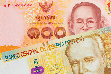 A macro image of a red, one hundred baht note from Thailand paired up with a beige, twenty sol bill from Peru.  Shot close up in macro.