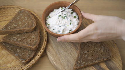 Spreading cream cheese with scallions on bread. Smear soft cheese on bread.