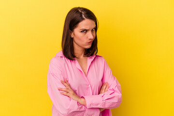 Young caucasian woman isolated on yellow background frowning face in displeasure, keeps arms folded.