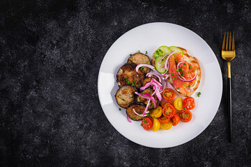 Delicious brunch  salmon  bread cream cheese sandwiches and arugula, tomatoes salad on a dark background. Top view, above
