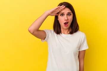 Young caucasian woman isolated on yellow background looking far away keeping hand on forehead.