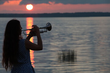 Silhouette of a person with a musical instrument trumpet on a sunset background