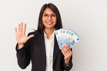 Young business latin woman holding bills isolated on white background smiling cheerful showing number five with fingers.