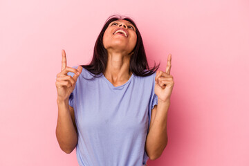 Young latin woman isolated on pink background pointing upside with opened mouth.