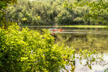 A photograph of a trio of kayakers on a river surrounded by a forest.