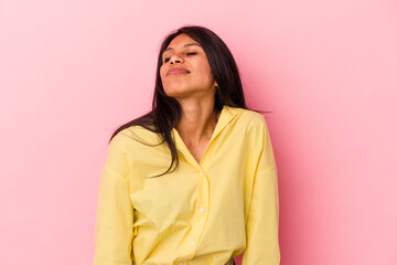 Young latin woman isolated on pink background shrugs shoulders and open eyes confused.