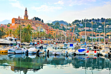 Fototapeta na wymiar Menton, French Riviera. View of the colorful old town from the boat filled harbor.