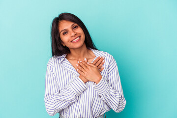 Fototapeta premium Young latin woman isolated on blue background has friendly expression, pressing palm to chest. Love concept.