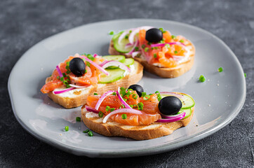 Toasts with cream cheese, smoked salmon, cucumber, black olives and red onion. Open sandwiches. Healthy care, super food concept.