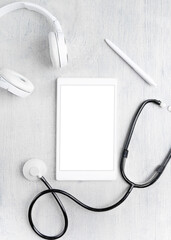 On a gray background, a tablet with a stethoscope and headphones. Online Medicine concept