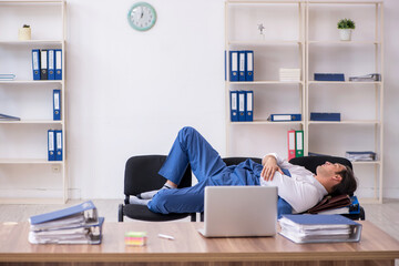Young male employee sleeping in the office on chairs
