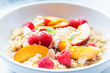 Summer oatmeal with raspberries, peaches and nuts. Healthy vegetarian food concept.