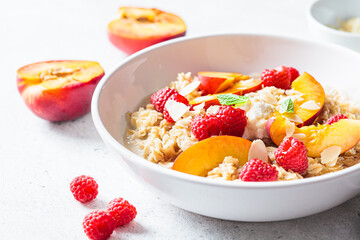Summer oatmeal with raspberries, peaches and nuts. Healthy vegetarian food concept.