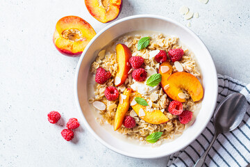 Summer oatmeal with raspberries, peaches and nuts. Healthy vegetarian food concept.