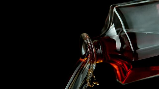 Super slow motion of pouring whiskey or rum, closeup detail on black background. Speed ramp effect. Camera motion. Filmed on high speed cinema camera, 1000fps