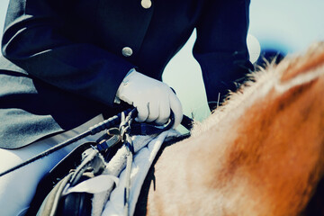 A rider's hand in a white glove with a rein. Equestrian sport.