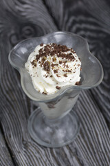 Dessert with cream and blueberries. Decorated with chocolate drops. In glass goblets. On black pine boards.