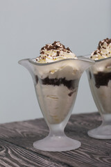 Dessert with cream and blueberries. Decorated with chocolate drops. In glass goblets. On black pine boards.