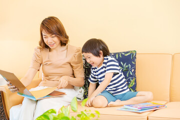 Young boy reading book and studies at home with his mom. Home school distance learning and happy learning online education concept