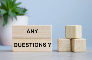 ANY QUESTIONS word on wooden cubes on white desk.