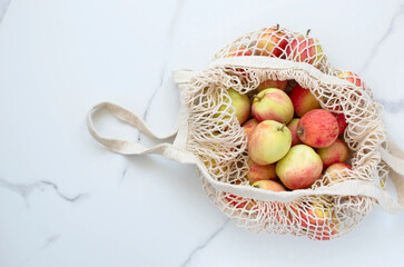 Top view of apples in an eco-friendly string bag on a white background.