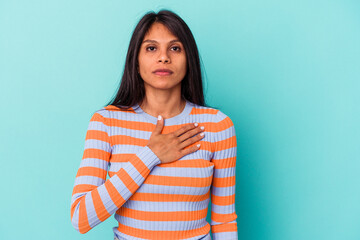 Fototapeta premium Young latin woman isolated on blue background taking an oath, putting hand on chest.