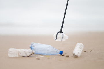Obraz premium Social and environmental issues. Environmental protection. Garbage collection on the seashore. Special stick for garbage collection. There are no people in the photo.