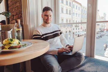 man working on laptop at cafe near big window copy space