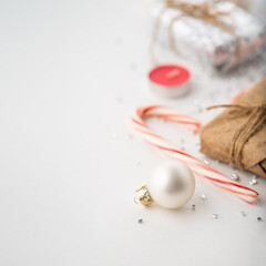 Christmas. New Year. Christmastide. Festive composition of Christmas balls, lollipops, gifts and candles. Simple white background. Bright hues. There is an empty space for your insert.