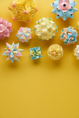 Set of multicolor handmade modular origami balls or Kusudama Isolated on yellow background. Visual...