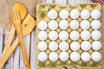 Aerial view of an egg carton container with organic white chicken eggs on a rustic wooden...