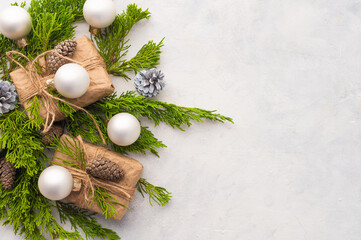 Fototapeta na wymiar Feast of Christmas. Gifts, surprises. Green coniferous branches decorated with white glass balls and cones. Gifts in beautiful packaging. White background. There is an empty space for your lettering.