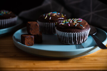 Birthday cupcake. Tasty chocolate cupcakes with cream and colored sprinkles. Sweet delicious dessert truffle and candy on a plate.