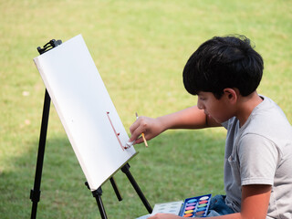 Cute Indian child painting with watercolors outdoor in the nature park. Concept of education outside of school..
