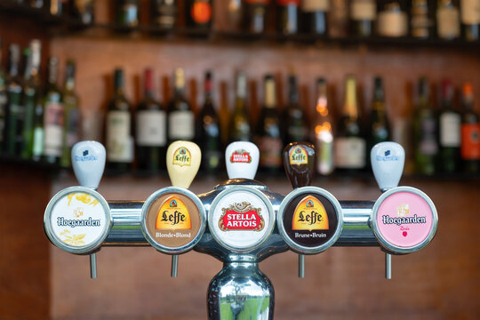 Thailand - July 2021: Various famous brand of draught beer such as Hoegaarden, Leffe and Stella are selling on beer tap at  local beverage bar. Close-up and selective focus.