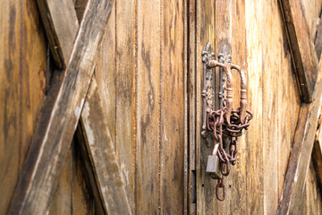 Close-up at rustic chain and keypad that locking on wooden gate of the farmhouse or barn entrance. Object and building, selective focus.