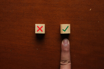 A finger pointing at the right symbol wooden block. Decision making concept.