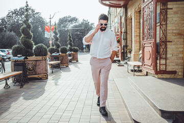 Handsome beard man posing in the street, hipster style, sunglasses, city, fashion model, business male, sunset time