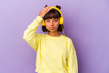 Young mixed race woman listening to music isolated on purple background being shocked, she has remembered important meeting.