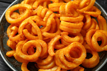 Golden Spicy Seasoned Curly Fries on rustic plate. ready to eat