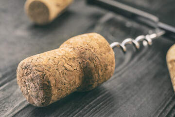 an old wooden champagne cork wound on metal chrome corkscrew lies on dark wooden surface, concept...