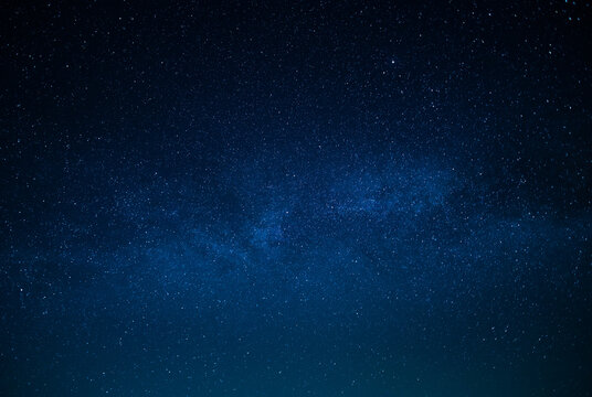 Milky Way. Night starry sky. Various shades of blue. Small stars twinkle in the sky. There is no one in the photo. High angle view. Wallpaper. Background. Texture.