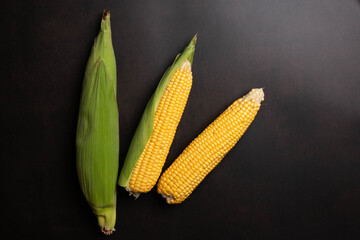 Fresh corn cobs on flat black background