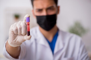 Young male chemist in pandemic concept