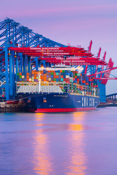 Hamburg, Germany - March 24, 2017: The container ship CMA CGM Benjamin Franklin is unloaded at the terminal Burchardkai (CTB) in the harbor at dusk.