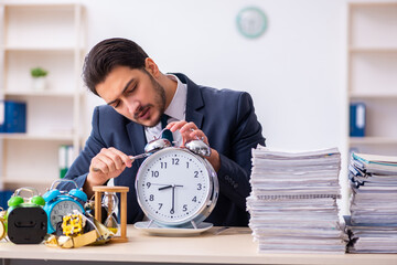Young businessman employee eating alarm-clock